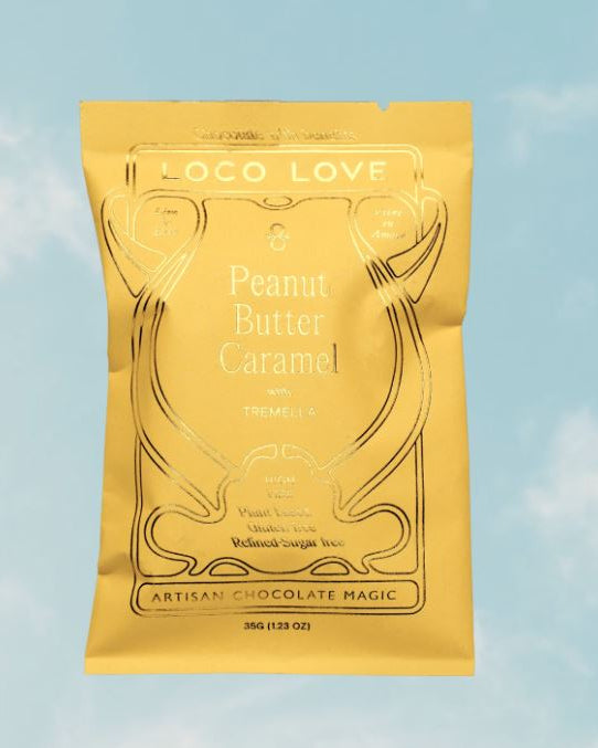 A yellow pouch of Loco Love Peanut Butter Caramel with Tremellio, floating against a light blue sky background with soft white clouds.