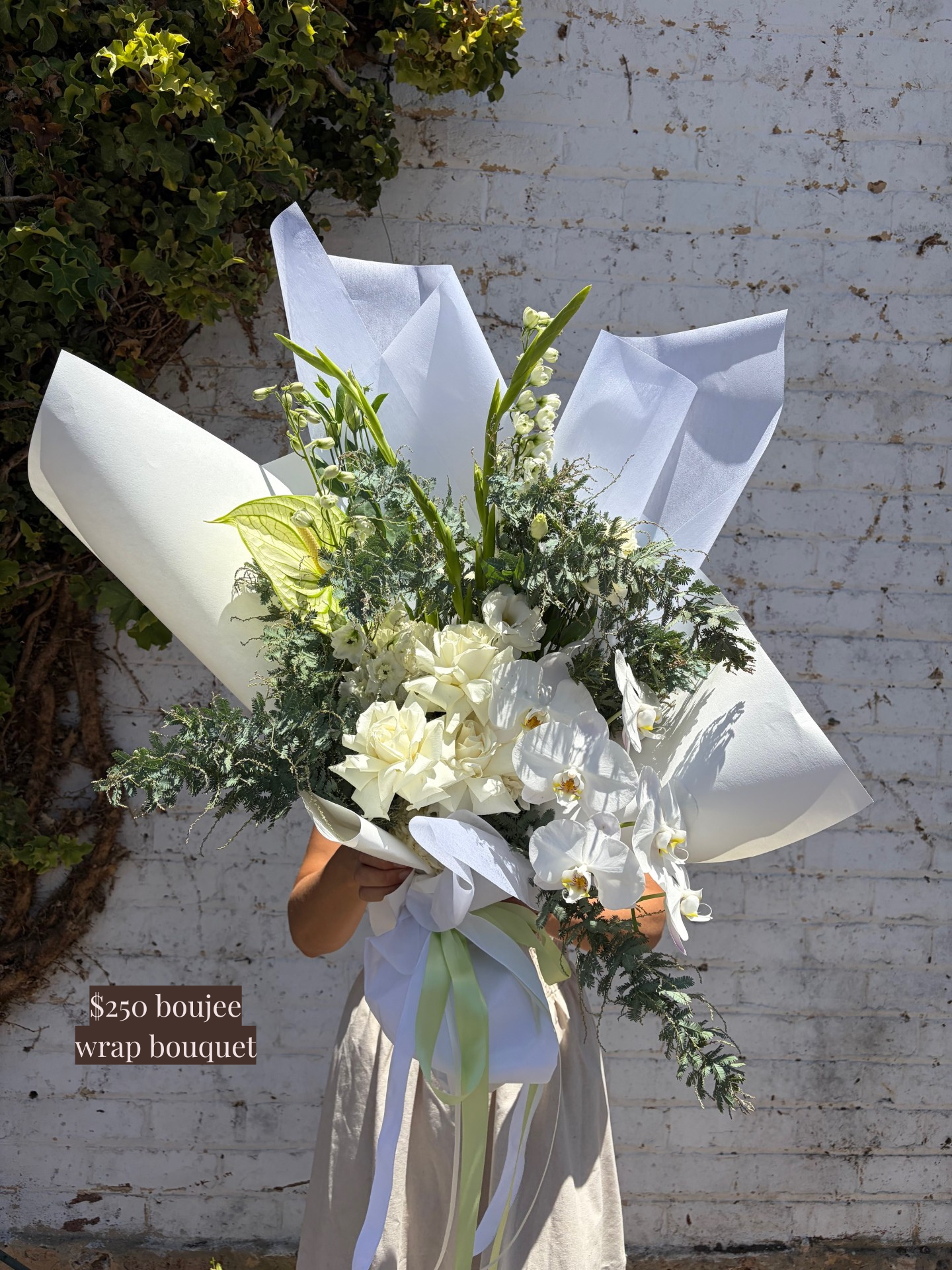 Bouquet of flowers wrapped in white paper with a brick wall background