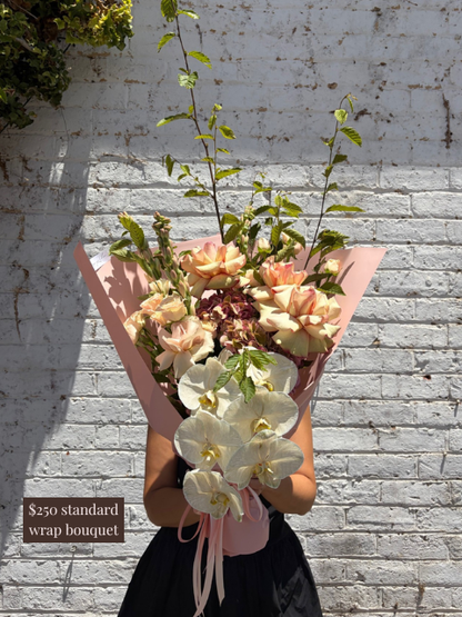 Bouquet of flowers held by a person against a textured wall.