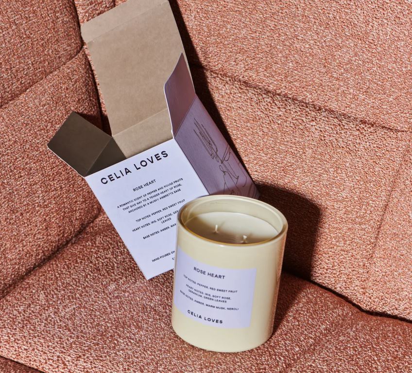 Candle with a label on a textured surface, accompanied by a card with 'Celia Loves' branding.