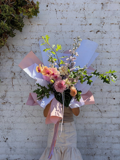 a person holding a large pastel flower bouquet