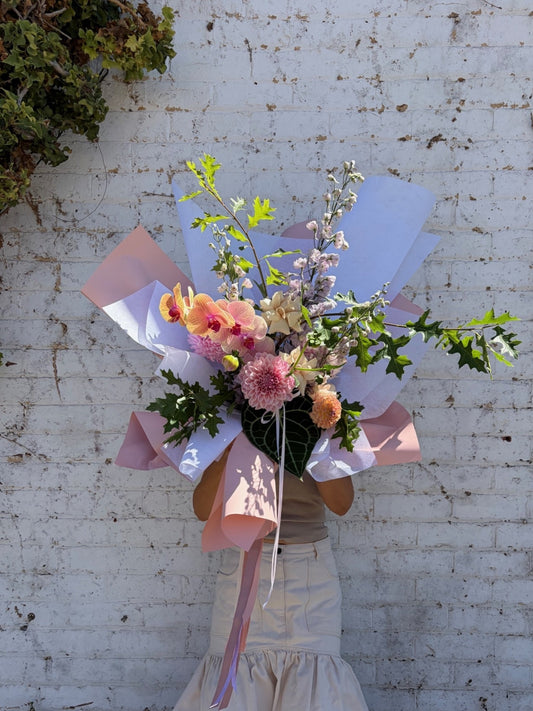 a person holding a large pastel flower bouquet