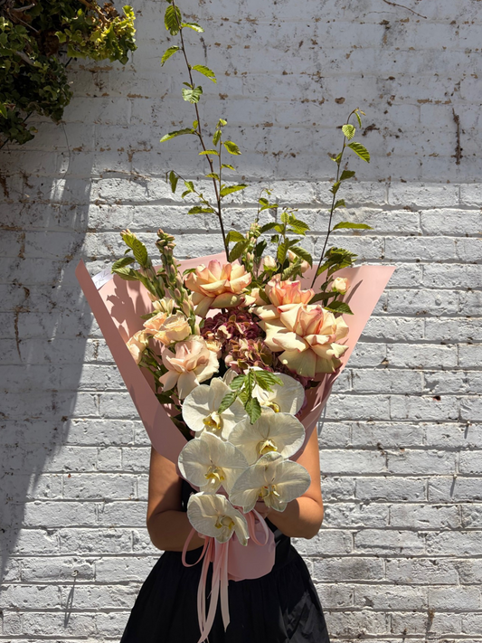Bouquet of flowers held against a textured white wall