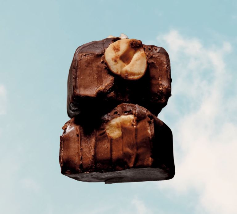 Two chocolate-covered treats with a visible filling against a blue sky background