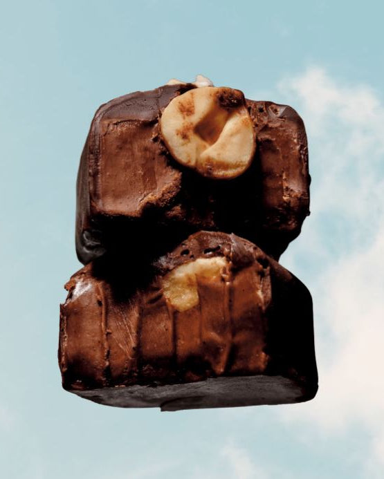 Two chocolate-covered treats with a visible filling against a blue sky background