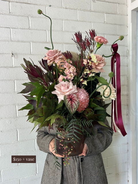 Person holding a bouquet of flowers against a white brick wall