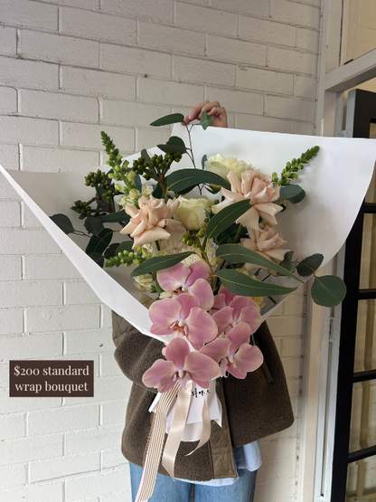 Person holding a bouquet of flowers with a white brick wall background