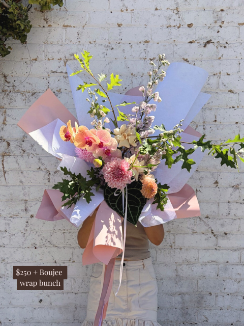 Bouquet of flowers with pink ribbon against a white brick wall