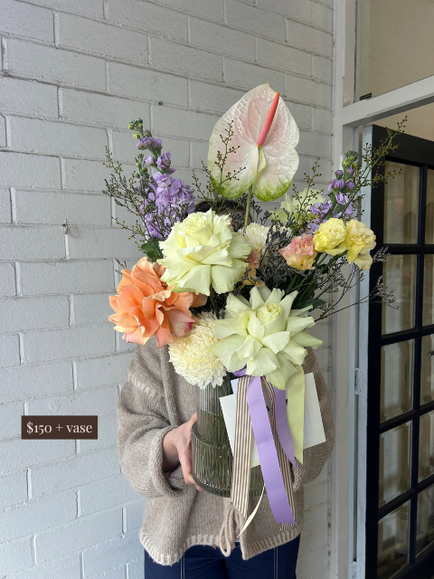Person holding a bouquet of flowers with a gray brick wall and door in the background