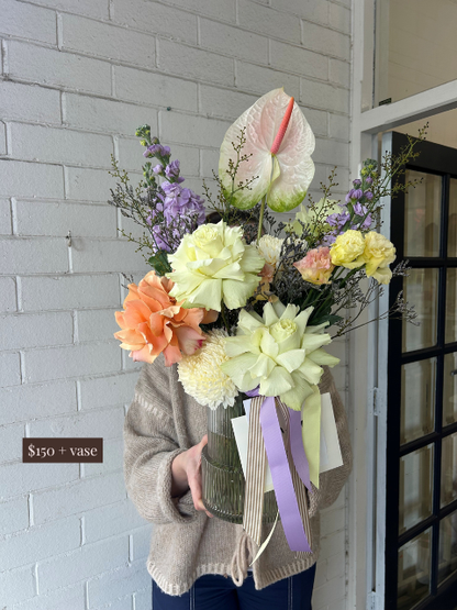 Person holding a bouquet of flowers with a gray brick wall and door in the background