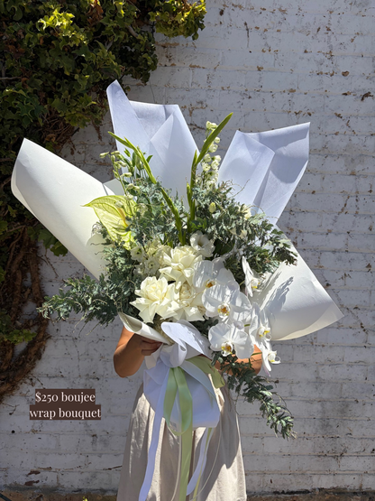 Bouquet of flowers wrapped in white paper with a brick wall background