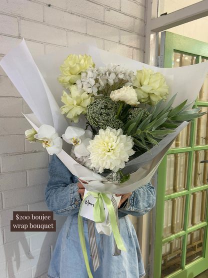 Bouquet of flowers wrapped in paper held by a person wearing a denim jacket.