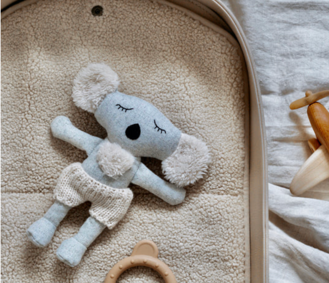 Plush toy bear with pom-pom details on a soft surface